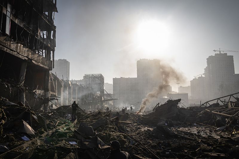 People walk through debris at the Retroville shopping mall following a Russian shelling attack in Kyiv, Ukraine, on March 21